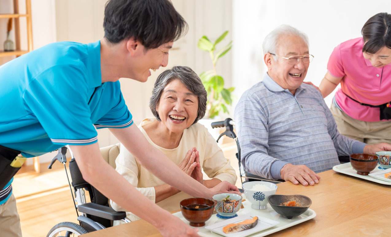 食事を運ぶ介護士と嬉しそうな高齢者の写真